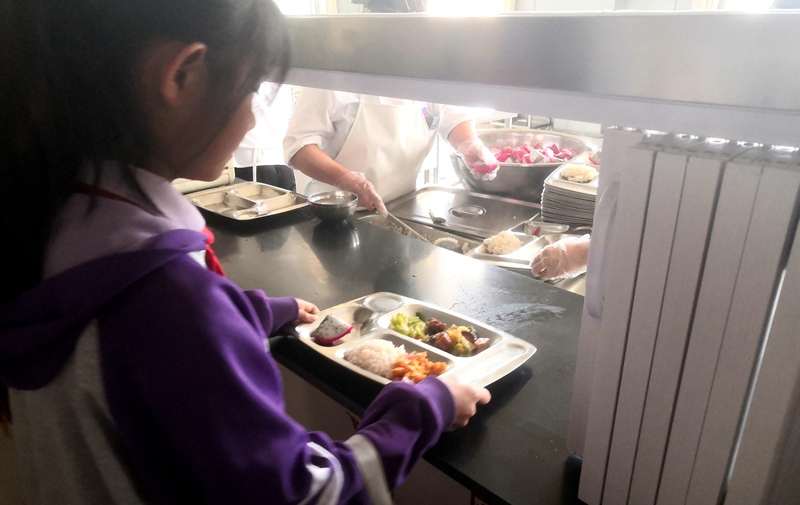 伊金霍洛旗第一小學(xué)學(xué)生正在打飯，今天的飯菜是三菜一湯外加水果，學(xué)生可以多次盛取，吃飽為止。人民網(wǎng)記者 孫博洋攝