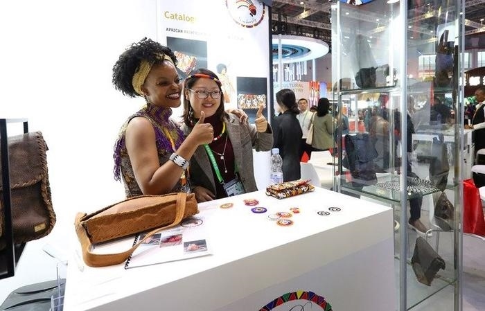 11月6日，一位參觀者（右）在第六屆進(jìn)博會國家展南非展臺試戴傳統(tǒng)首飾。