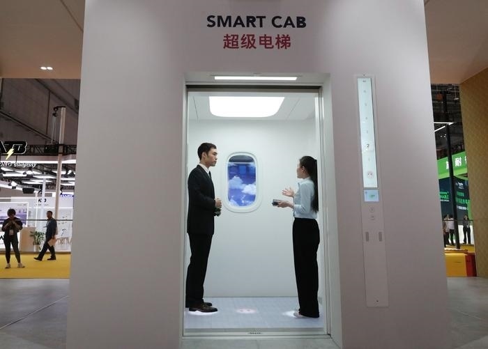 11月5日，工作人員（右）在第六屆進(jìn)博會上向參觀者介紹奧的斯公司全新推出的超級電梯。